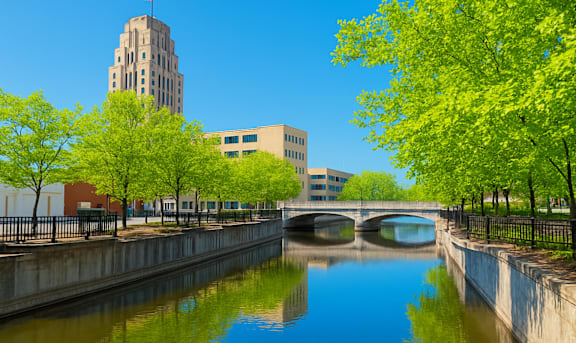 A river flows under a bridge with a building in the background.