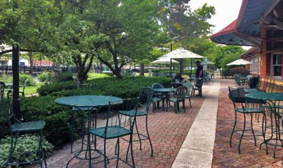 A patio with tables and chairs surrounded by greenery.