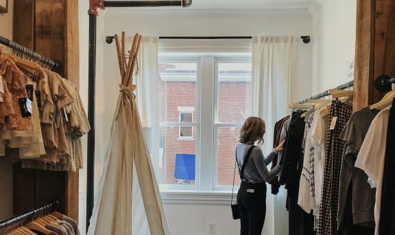 a woman looking at clothes on a rack in a closet