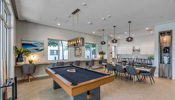 A pool table is in the middle of a room with a bar and a dining table.