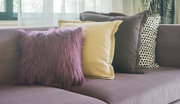 a purple sofa with purple and yellow cushions