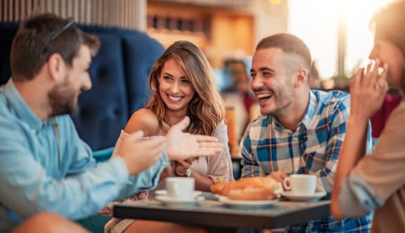 a group of people sitting around a table talking and laughing