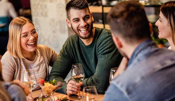Four people are sitting around a table, laughing and enjoying each other's company.