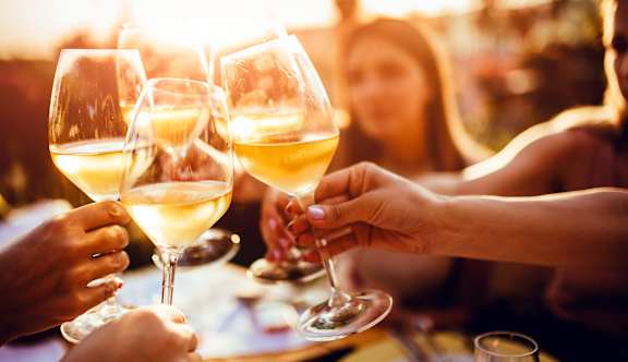 A group of people toasting with glasses of white wine.