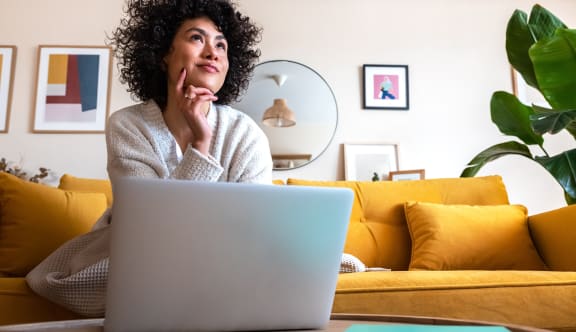 a woman sitting on a couch with a laptop in front of her