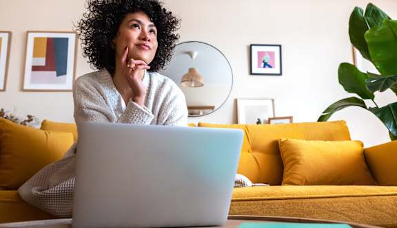 A person with curly hair is sitting in front of a laptop.