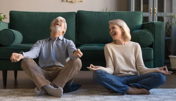 a man and a woman laughing while sitting on the floor in front of a couch