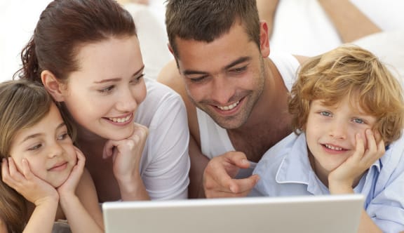 a family lying on the floor looking at a laptop