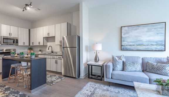 a spacious living room with a kitchen in the background