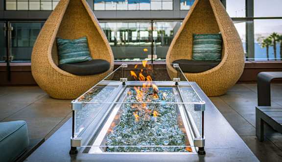 A modern living room with a glass table and two hanging chairs.