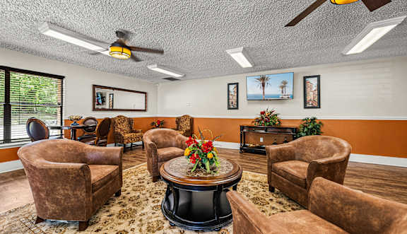 A living room with a brown sofa, a coffee table, and a ceiling fan.