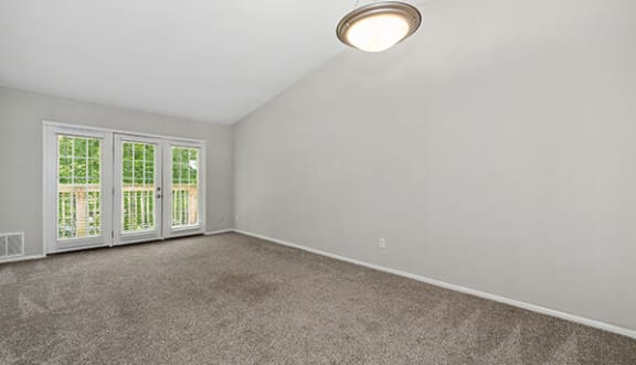 an empty living room with large windows and a ceiling light