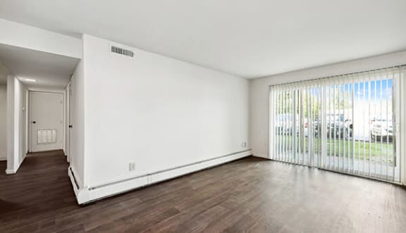 an empty living room with wood floors and a large window