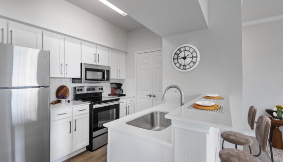 a kitchen with white cabinets and a large white island with a stainless steel sink and dishwasher