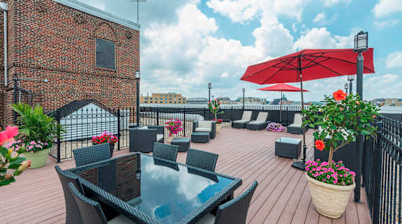 A patio with a table and chairs under a red umbrella.