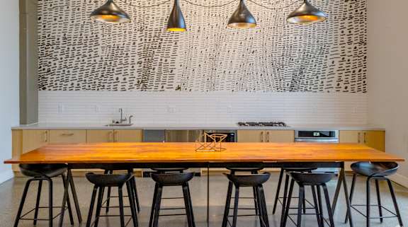 A kitchen with a wooden table and black stools.