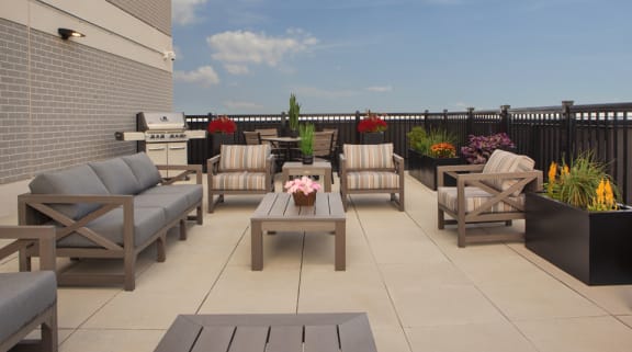 a patio with chairs and tables and a grill on a roof