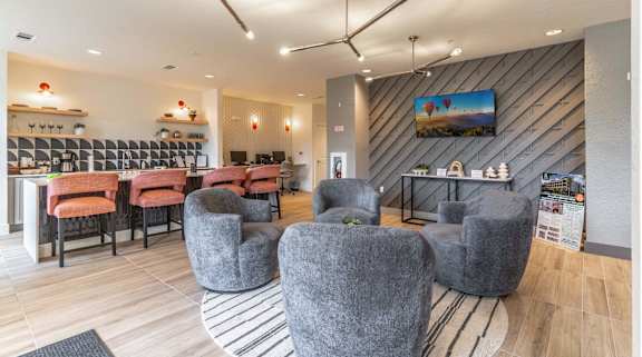 A modern lounge area with grey chairs and a wooden floor.