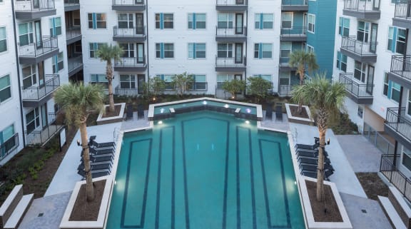 an apartment pool with an apartment building in the background at Gatsby on Ross, Dallas, Texas