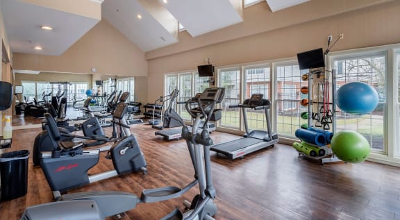 a gym with treadmills and other exercise equipment in a large room with windows