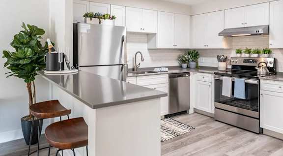 A modern kitchen with a stainless steel refrigerator and a wooden stool.