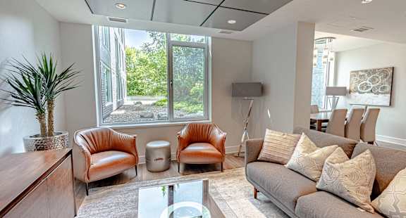 a living room with a couch and chairs and a large window