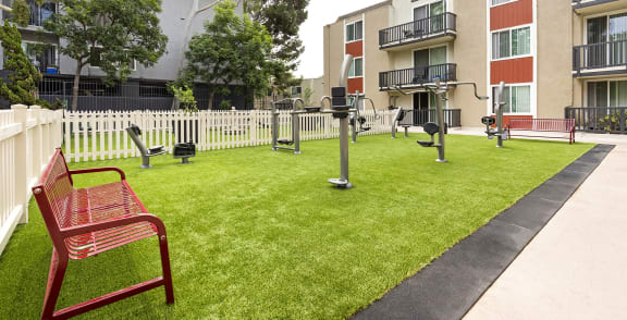 a red bench sitting on a lawn in front of an apartment building