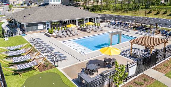 A large outdoor pool area with a small putting green and a clubhouse.