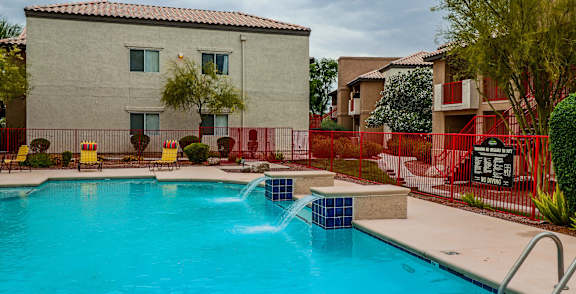 A pool surrounded by palm trees and a building.