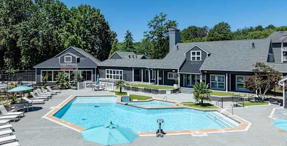 A swimming pool surrounded by a grassy area and apartment buildings.