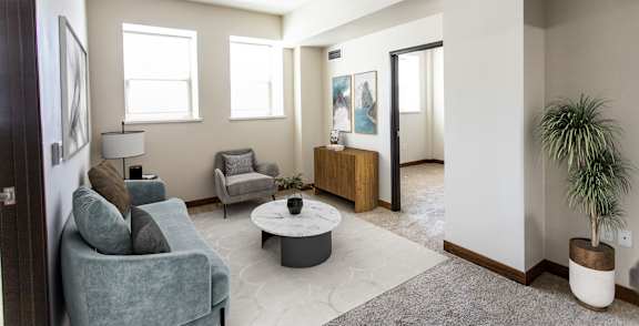 A living room with a grey couch, a white coffee table, and a plant.
