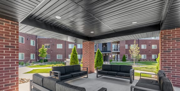 a covered patio with couches and chairs and a brick building