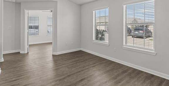 an empty living room with a ceiling fan and three windows