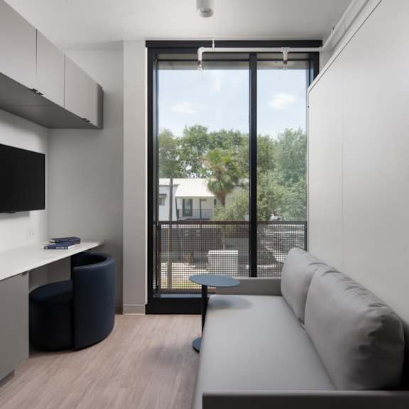 A modern living room with a grey couch and a black TV.