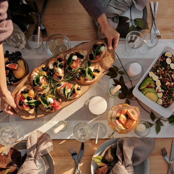 people are eating pizza and salads on a table