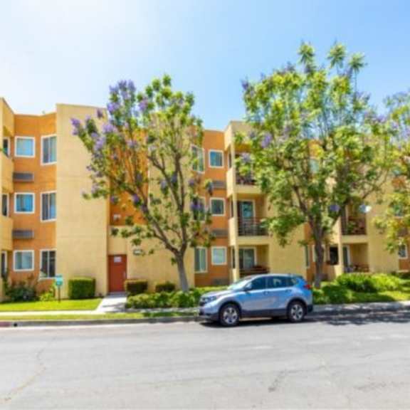 a sunny day at a residential building with cars parked in front.