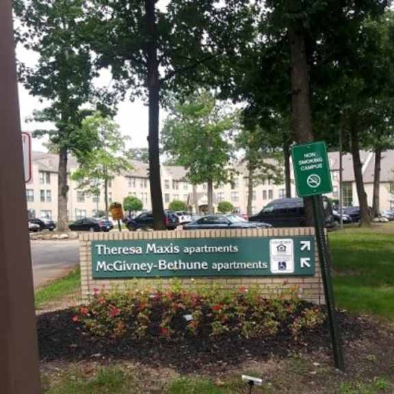 a sign for theresa maxis apartments and mcgivney-bethune apartments is in front of a parking lot.