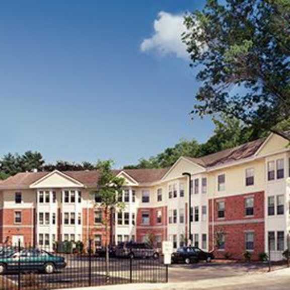 apartment complex with red and white buildings and green trees.