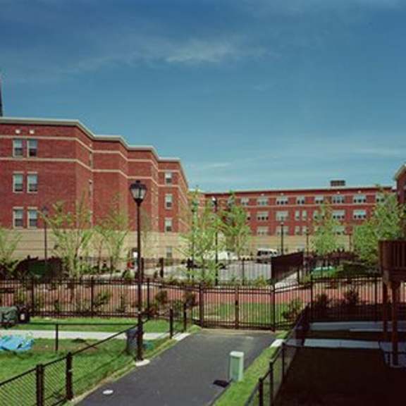 a long brick building with a black fence in front.