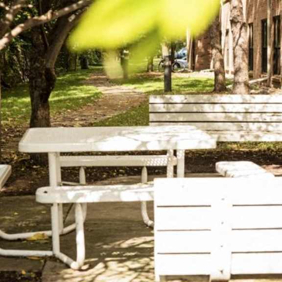 a white bench and table are in a park.
