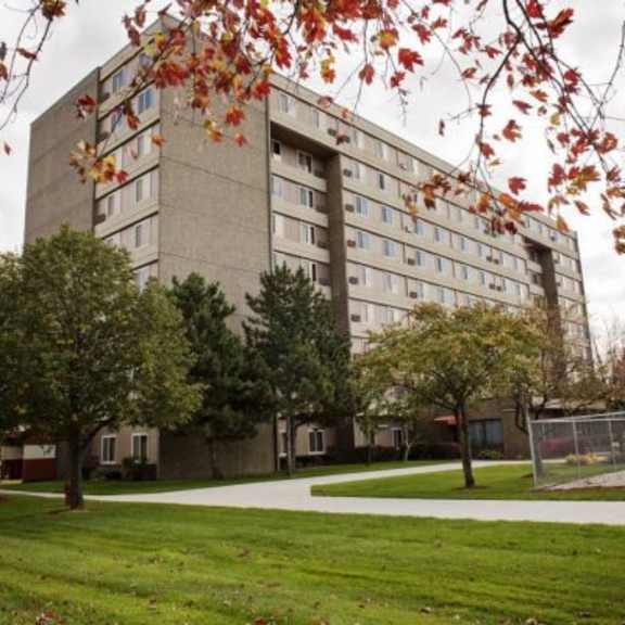 a large building with a lot of windows is surrounded by trees with red leaves.