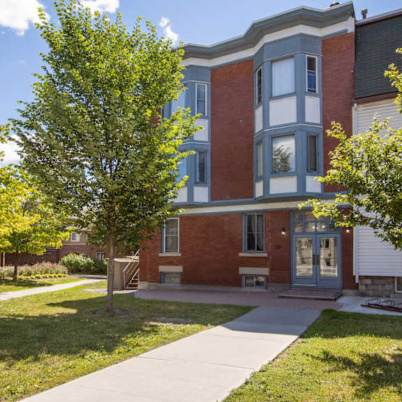 a red brick building with a green tree in front.