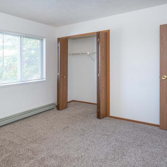 an empty bedroom with a closet and a window