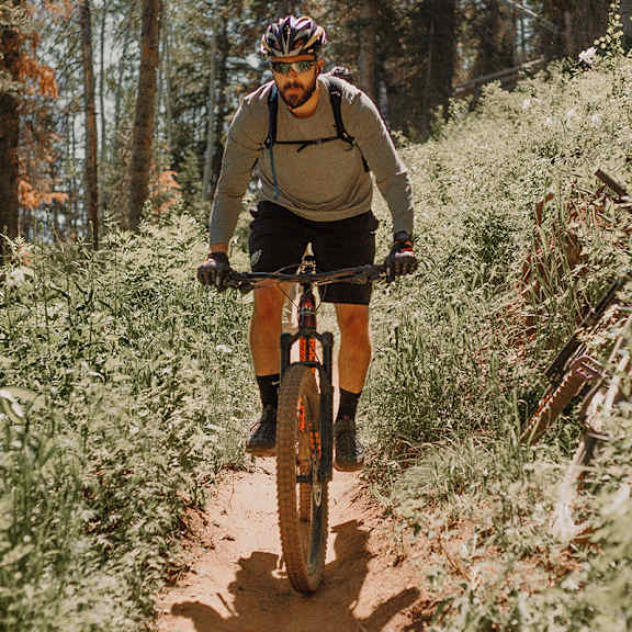 A man riding a bicycle on a trail in the woods.