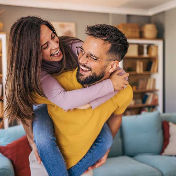 a man is giving a woman a piggyback ride in a living room.