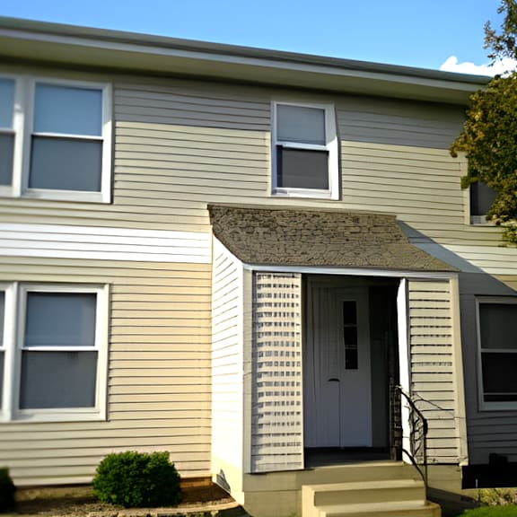 a yellow house with a white door and a tree in front of it
