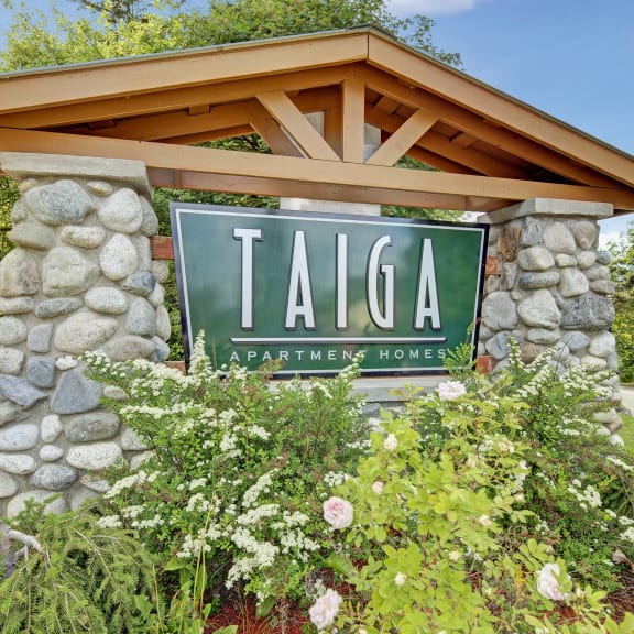 a sign for taiga apartment homes in front of a stone and wood sign