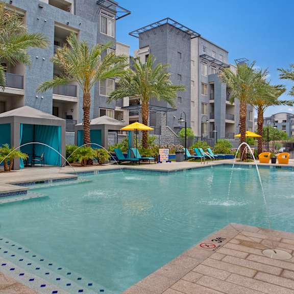 a pool surrounded by palm trees and lounge chairs.