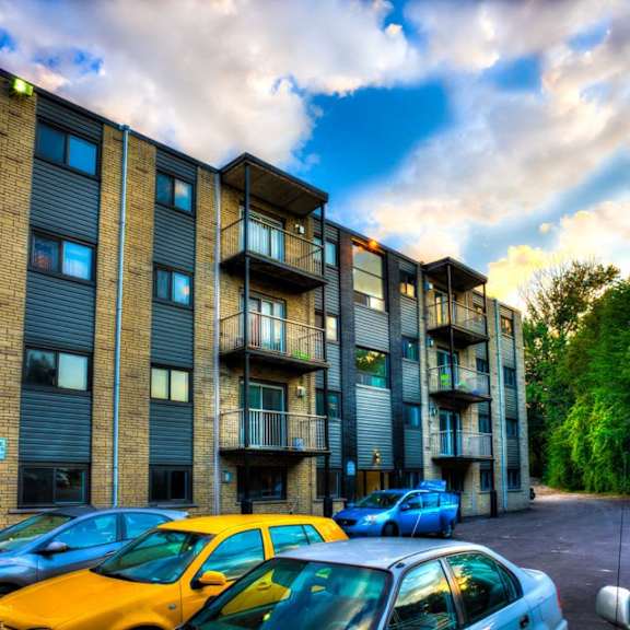 a parking lot with cars parked in front of a multi-story apartment building.