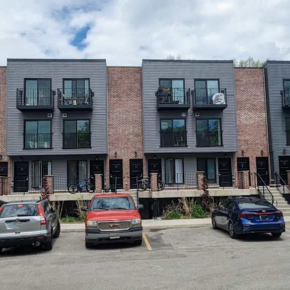 a row of modern apartment buildings with cars parked in front.